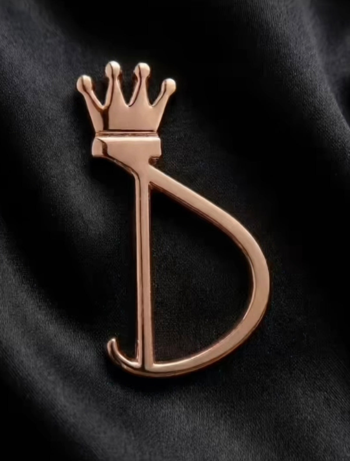 Herraje rosa dorado de la D coronada sobre denim